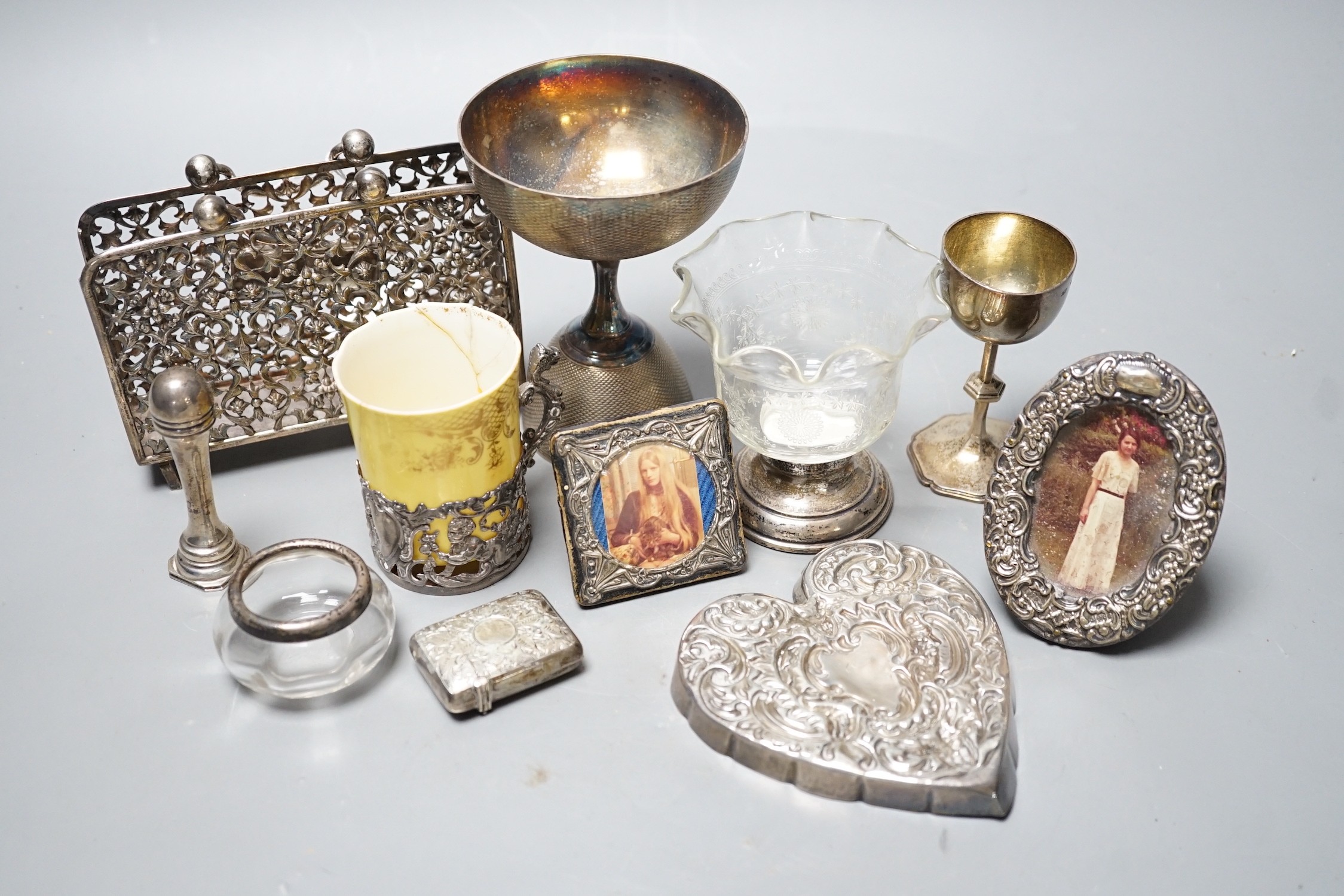 A small group of collectable items including a silver stationary rack, Laurence Emanuel, Birmingham, 1901, height 9.7cm, a silver communion goblet, silver mounted porcelain coffee cup, silver mounted glass vase, silver v
